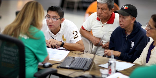 MIAMI, FL - MARCH 20: Paul Paucar (L-R), Homero Paucar, Giovanny Paucar and Ivonne Cucalon sit with, Jessica Adames, an insurance agent from Sunshine Life and Health Advisors as they try to purchase health insurance under the Affordable Care Act at a store setup in the Mall of Americas on March 20, 2014 in Miami, Florida. The owner of Sunshine Life and Health Advisors, Odalys Arevalo, said she has seen a surge in people, some waiting up to 3 hours or more in line, trying to sign up for the Affordable Care Act before the open enrollment period for individual insurance ends on March 31. (Photo by Joe Raedle/Getty Images)