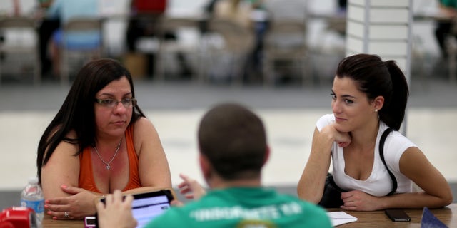 MIAMI, FL - MARCH 20:  Lidice Bacallao (L) andYislaine Diaz sit with Amaury Garcia an insurance agent from Sunshine Life and Health Advisors as they purchase individual health insurance policies under the Affordable Care Act at a store setup in the Mall of Americas on March 20, 2014 in Miami, Florida. The owner of Sunshine Life and Health Advisors, Odalys Arevalo, said she has seen a surge in people, some waiting  up to 3 hours or more in line, trying to sign up for the Affordable Care Act before the open enrollment period for individual insurance ends on March 31.  (Photo by Joe Raedle/Getty Images)
