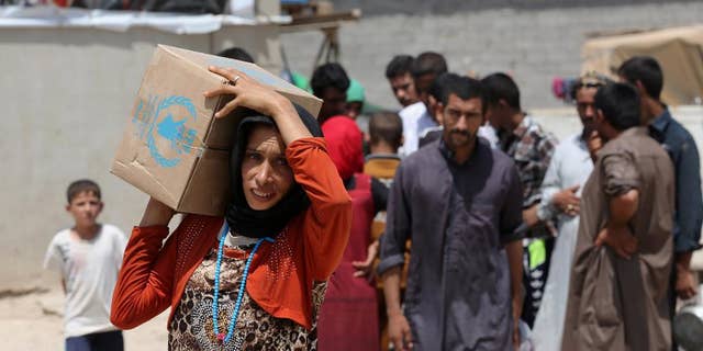 A woman carries a box of food from the World Food Programme at al-Takia refugee camp in Baghdad, Iraq, Thursday, July 30, 2015. The number of people displaced within Iraq due to violence and fighting by the Islamic State group has exceeded 3 million, the United Nations said in June. (AP Photo/Khalid Mohammed)