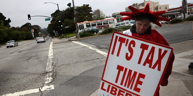 SAN FRANCISCO, CA - APRIL 14: Aaron Lee holds a sign advertising income tax services for Liberty Tax Service on April 14, 2014 in San Francisco, California.  Tax preparers are helping last minute tax filers ahead of the April 15th deadline to file state and federal income taxes.  The Internal Revenue Service is expecting an estimated 35 million returns in the week leading up to the deadline. 