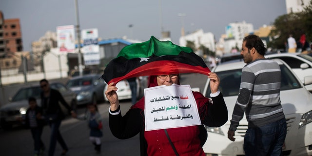 Nov. 22, 2013: A Libyan woman waves a Libyan flag to support the new national army and the police corps during a protest in Tripoli, Libya. Thousands of protesters have gathered in Libya's capital to call on unlawful armed groups to leave the city, a week after militiamen killed more than 40 people. The head of Tripoli's local council, Al-Sadat al-Badri, told the crowd on Friday that the city will remain on strike until the capital and its surroundings are free of militias. The Arabic reads, "Down all the armed group. Yes to the army and the police only."