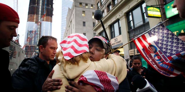 Dionne Layne, facing camera, hugs Mary Power as they react to the news of the death of Osama bin Laden, Monday, May 2, 2011 in New York. At left is the rising tower, 1 World Trade Center, also known as the Freedom Tower. (AP Photo/Mark Lennihan)