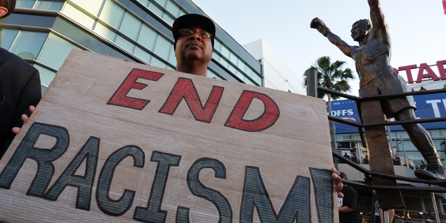 LOS ANGELES, CA - APRIL 29: Dexter McLeod holds a sign protesting racist comments made by L.A. Clippers owner Donald Sterling outside Staples Center before a playoff game on April 29, 2014 in Los Angeles, California. Clippers owner Donald Sterling was banned for life today by the NBA and barred from having any association with the team and ordered to pay a $2.5 million fine. (Photo by Jonathan Alcorn/Getty Images)