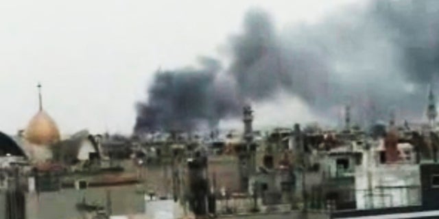 Monday, March 26: This image made from amateur video and released by Shaam News Network purports to show smoke rising from buildings in Homs, Syria. Syrian troops shelled rebel-held neighborhoods in the central city of Homs on Monday with at least five people seriously wounded.