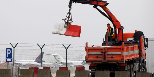 Workers place concrete blocks to block access to a security fence next to the tarmac, at Brussels international airport, Tuesday, Feb. 19, 2013. Eight masked gunmen made a hole in a security fence at Brussels' international airport, drove onto the tarmac and snatched some $50 million worth of diamonds from the hold of a Swiss-bound plane without firing a shot, authorities said Tuesday. (AP Photo/Yves Logghe)