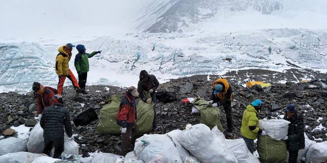 In this Monday, May 8, 2017 photo released by Xinhua News Agency, people collect garbage at the north slope of the Mount Qomolangma in southwest China's Tibet Autonomous Region. Workers and volunteers collected four tons of garbage from the Chinese north side of Mount Everest in the first five days of a cleanup operation.