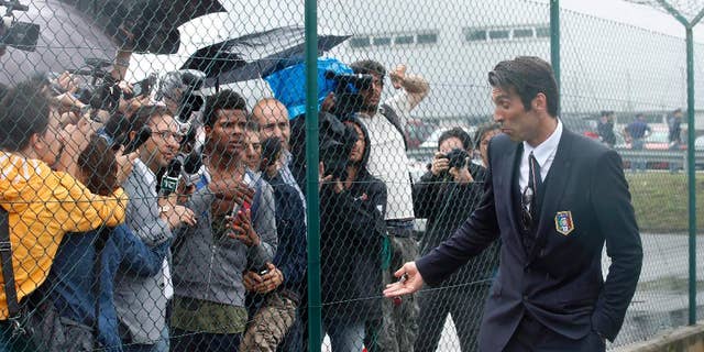 Italy goalkeeper Gianluigi Buffon talks to reporters upon his arrival with his teammates at Malpensa airport after landing from Brazil, in Milan, Italy, Thursday, June 26, 2014. Italy was disqualified from the World Cup after loosing to Uruguay in their group stage round. (AP Photo/Luca Bruno)