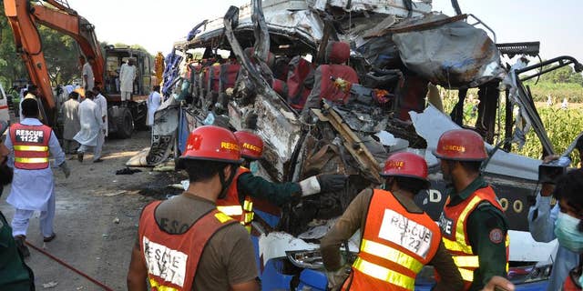 A Pakistani rescue team work on the wreckage of a deadly accident involving two buses, in Khanpur, Monday, Oct. 17, 2016. Pakistani officials say the death toll from a head-on collision of two passenger buses in central Pakistan is over two dozen. They say tens of people were injured in the crash, many of whom remain in critical condition. Police say speeding seems to have been the cause of the accident, which occurred on a dangerous curve in Rahim Yar Khan district. (AP Photo/Waleed Saddique)