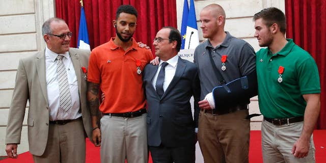 CORRECTS SADLER’S SCHOOL TO SACRAMENTO STATE UNIVERSITY, INSTEAD OF SACRAMENTO UNIVERSITY - From the left, British businessman Chris Norman, Anthony Sadler, a senior at Sacramento State University in California, French President Francois Hollande, U.S. Airman Spencer Stone, and Alek Skarlatos a U.S. National Guardsman from Roseburg, Ore., pose at the Elysee Palace, Monday, Aug. 24, 2015 in Paris, France. Hollande pinned the Legion of Honor medal on Stone, Skarlatos and Sadler, three long-time friends who subdued a gunman on Friday, Aug. 21, as he moved through a speeding train with an assault rifle strapped to his bare chest. Norman also jumped into the fray. (AP Photo/Michel Euler, Pool)