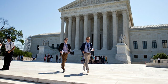 Gregory Briker, left, and John Bat, both with CBS News, run from the Supreme Court in Washington, Monday, June 20, 2016, with papers announcing court decisions. (AP Photo/Alex Brandon)
