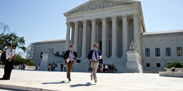 Gregory Briker, left, and John Bat, both with CBS News, run from the Supreme Court in Washington, Monday, June 20, 2016, with papers announcing court decisions. (AP Photo/Alex Brandon)