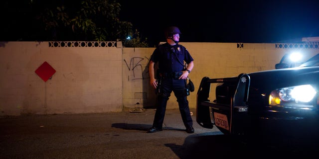 ANAHEIM, CA - JULY 25: A police officer stands guard after protesters set fire to a near by trash bin during a demonstration to show outrage for the fatal shooting of Manuel Angel Diaz, 25, at Anaheim City Hall on July 24, 2012 in Anaheim, California. Diaz was fatally shot on July 21 by an Anaheim police officer and has sparked days of protests by the angered community. (Photo by Jonathan Gibby/Getty Images)