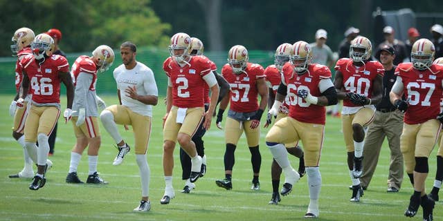 San Francisco 49ers quarterback Colin Kaepernick, in white shirt, leads his team in drills in a joint football practice with the Baltimore Ravens , Saturday, Aug. 9, 2014, in Owings Mills, Md.(AP Photo/Gail Burton)