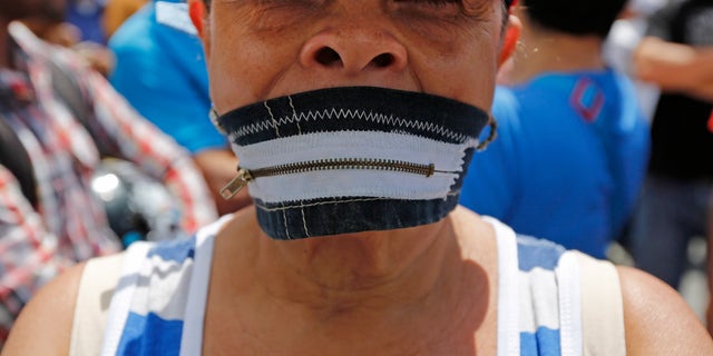 A protester wears a zipper over her mouth at a demonstration demanding the release of Metropolitan Mayor Antonio Ledezma in Caracas, Venezuela, Friday, Feb. 20, 2015. Demonstrators are condemning last night's surprise arrest of the Caracas' mayor for allegedly plotting to overthrow the government of President Nicolas Maduro. Late Thursday Maduro said that Ledezma, one of the most vocal opposition leaders, would be punished for trying to sow unrest in Venezuela. (AP Photo/Ariana Cubillos)