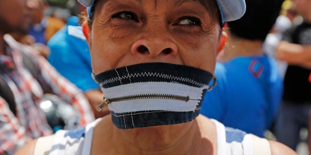 A protester wears a zipper over her mouth at a demonstration demanding the release of Metropolitan Mayor Antonio Ledezma in Caracas, Venezuela, Friday, Feb. 20, 2015. Demonstrators are condemning last night's surprise arrest of the Caracas' mayor for allegedly plotting to overthrow the government of President Nicolas Maduro. Late Thursday Maduro said that Ledezma, one of the most vocal opposition leaders, would be punished for trying to sow unrest in Venezuela. (AP Photo/Ariana Cubillos)