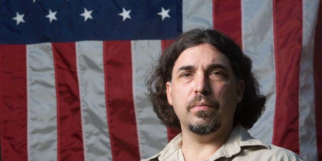Brian Browne, 45, stands in front of one of the many flags he collects at his home on Tuesday, Sept. 27, 2016, in Everett, Wash. Browne, who turned in an American flag raised at ground zero on Sept. 11 to a Washington state courthouse, has been identified. The Daily Herald reports that Browne, had seen the coverage of the flag's return to New York earlier this month and contacted authorities. (Andy Bronson/The Herald via AP)
