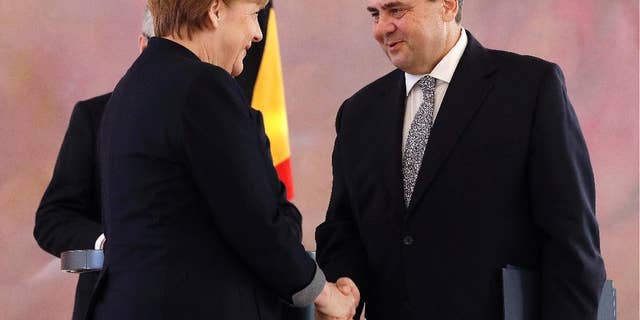Former German Minister for Economic Affairs and Energy and new Foreign Minister Sigmar Gabriel shakes hands with German Chancellor Angela Merkel after he received his notices of dismissal and documents of appointment by German President Joachim Gauck in Berlin, Germany, Friday, Jan. 27, 2017. (AP Photo/Michael Sohn)