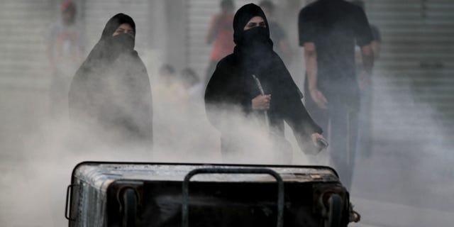 Bahraini anti-government protesters block a road with burning debris to slow approaching riot police in Sanabis, Bahrain, Monday, April 15, 2013. The race is to be held Sunday. Bahrain's government has backed proposals to impose penalties of up five years in prison for insulting the Gulf state's king or its national symbols, the media said Monday. (AP Photo/Hasan Jamali)
