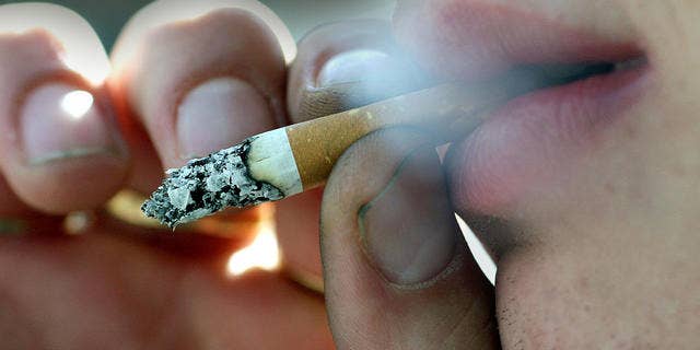 A person smokes outside his place of work in Belfast, Northern Ireland, Monday, April, 30, 2007. A smoking ban in all public places has come into effect from Monday in Northern Ireland. (AP Photo/Peter Morrison)