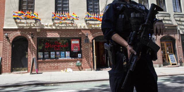 FILE - In a June 12, 2016 file photo, an armed police officer stands guard outside the Stonewall Inn, in New York. Sunday's mass shooting the Pulse nightclub, in which gunman Omar Mateen killed dozens of people before dying in a gun battle, prompted an outpouring of reminiscence and reflection on that vital roles that such clubs have played for many lesbians, gays, bisexuals and transgender people across the U.S. (AP Photo/Mary Altaffer, File)