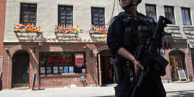 FILE - In a June 12, 2016 file photo, an armed police officer stands guard outside the Stonewall Inn, in New York. Sunday's mass shooting the Pulse nightclub, in which gunman Omar Mateen killed dozens of people before dying in a gun battle, prompted an outpouring of reminiscence and reflection on that vital roles that such clubs have played for many lesbians, gays, bisexuals and transgender people across the U.S. (AP Photo/Mary Altaffer, File)