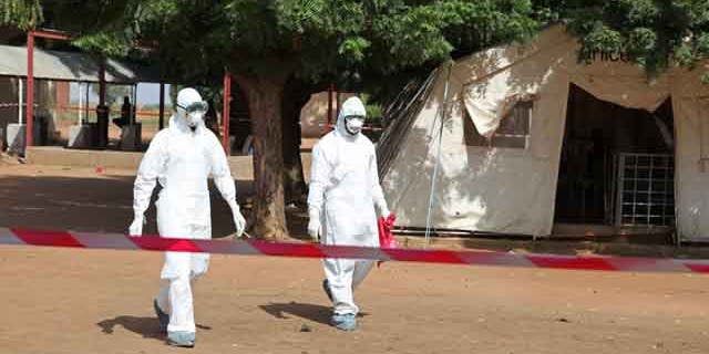 October 25, 2014: Health workers walk towards an area used for Ebola quarantine after they worked with diseased Fanta Kone at a Ebola virus center in Kayes, Mali. (AP Photo/Baba Ahmed)