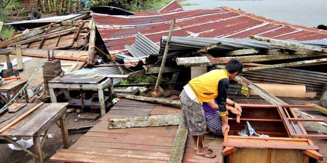 Dec. 4, 2012: Residents prepare to assess their house which was damaged by Typhoon Bopha in Butuan city in southeastern Philippines.