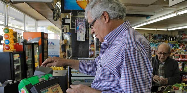 Farouk Tawfik sells Powerball lottery tickets at the Time Saver Food Mart Wednesday, Feb. 11, 2015, in Tampa, Fla. The Powerball jackpot has climbed to $500 million, making Wednesday night's drawing the fifth largest prize in U.S. history. (AP Photo/Chris O'Meara)