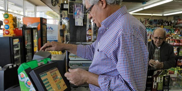 Farouk Tawfik sells Powerball lottery tickets at the Time Saver Food Mart Wednesday, Feb. 11, 2015, in Tampa, Fla. The Powerball jackpot has climbed to $500 million, making Wednesday night's drawing the fifth largest prize in U.S. history. (AP Photo/Chris O'Meara)