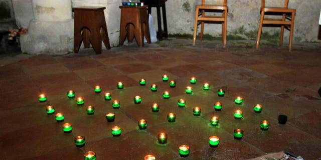 Candles and a bunch of flowers are placed on the ground inside a church in Petit-Palais-et-Cornemps, near the crash site of Puisseguin, southwestern France, in memory of the 43 victims of a road crash, Friday, Oct. 23, 2015. A truck and a bus transporting retirees on a day trip collided and caught fire Friday on a country road in wine country in southwest France, killing 43 people and gravely injuring at least four others, authorities said. (AP Photo/Bob Edme)