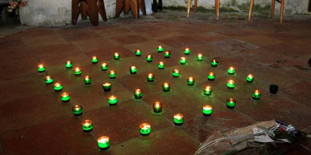 Candles and a bunch of flowers are placed on the ground inside a church in Petit-Palais-et-Cornemps, near the crash site of Puisseguin, southwestern France, in memory of the 43 victims of a road crash, Friday, Oct. 23, 2015. A truck and a bus transporting retirees on a day trip collided and caught fire Friday on a country road in wine country in southwest France, killing 43 people and gravely injuring at least four others, authorities said. (AP Photo/Bob Edme)