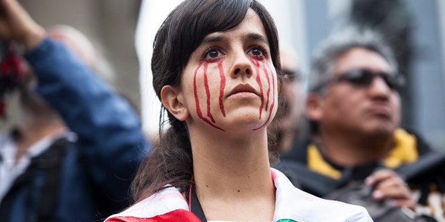 A young woman with fake blood painted on her face watches a protest for 43 missing students from Ayotzinapa Normal school in Mexico City, Mexico. (Photo by Brett Gundlock/Getty Images)