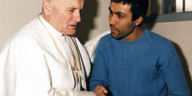 FILE - This Dec. 27, 1983 file photo provided by Vatican newspaper L'Osservatore Romano, shows Pope John Paul II, left, talking with his would-be assassin Mehmet Ali Agca, of Turkey, in Agca's prison cell in Rome. The Turkish gunman who shot Pope John Paul II has changed his story once again, saying in a new autobiography that Iran's late leader Ayatollah Ruhollah Khomeini personally told him to kill the pope. Mehmet Ali Agca writes in "They Promised Me Paradise,'' released Thursday Feb. 1, 2013 in Italy, that he was trained in Iran by Khomeini's forces after escaping from a Turkish prison, and that the Iranian leader himself told him to kill John Paul in the name of God. (AP Photo/Arturo Mari, L'Osservatore Romano)