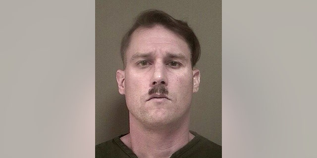 This photo provided Monday May 16, 2016 by New Jersey's Ocean County Jail shows Bruce Post III, who was arrested by Lacey, N.J., police on Sunday, May 15, 2016 after authorities ay they found a large cache of weapons and ammunition in the New Jersey Pinelands. Police were in the area looking for trespassers and criminal activity when they found the 42-year-old dressed in combat gear, another man nearby, and an AK-47, a 9mm handgun, eight 30-round magazines, a 100-round drum magazine and other ammunition police said was hidden in the woods. Post was charged with illegally possessing a weapon as a felon and several weapons counts. (Ocean County Jail via AP)