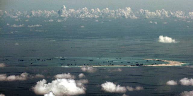 FILE - In this May 11, 2015, file photo, this aerial photo taken through a glass window of a military plane shows China's alleged on-going reclamation of Mischief Reef in the Spratly Islands in the South China Sea. China will complete land reclamation projects on its disputed South China Sea territorial claims as planned within 