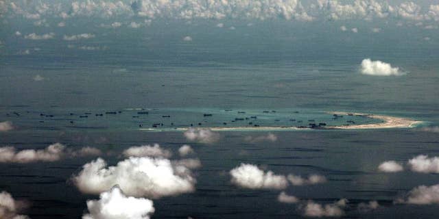 FILE - In this May 11, 2015, file photo, this aerial photo taken through a glass window of a military plane shows China's alleged on-going reclamation of Mischief Reef in the Spratly Islands in the South China Sea. China will complete land reclamation projects on its disputed South China Sea territorial claims as planned within "upcoming days," the Foreign Ministry said Tuesday, June 16, 2015. (Ritchie B. Tongo/Pool Photo via AP)