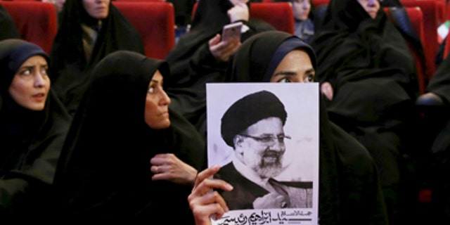 An Iranian holds up a poster of Iranian cleric Ebrahim Raisi, a conservative presidential candidate in the upcoming presidential election, at a campaign rally in Tehran, Iran, Wednesday, April 26, 2017. (AP Photo/Ebrahim Noroozi)