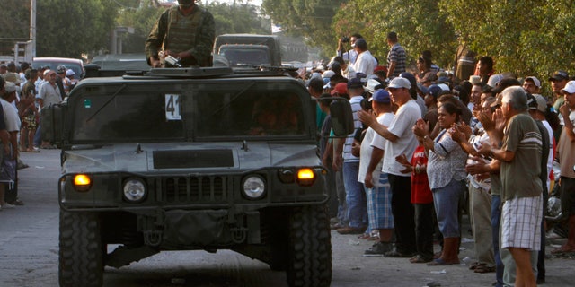 Mexican army soldiers enter the town of La Ruana, Michoacan, Mexico, Monday, May 20, 2013. Residents of western Mexico towns who endured months besieged by a drug cartel are cheering the arrival of hundreds of Mexican army troops. Hundreds of people in the state of Michoacan have taken up arms to defend their villages against drug gangs, a vigilante movement born of frustration at extortion, killings and kidnappings in a region wracked by violence. (AP Photo/Marco Ugarte)