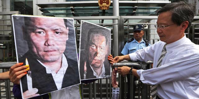 FILE - In this May 14, 2014 file photo, anti-Beijing protesters, holding pictures of human rights lawyer Pu Zhiqiang, protest outside the Chinese liaison office to demand Pu's release, in Hong Kong. Pu, a prominent Chinese rights lawyer whose trial is drawing near on charges of inciting ethnic hatred and provoking trouble has been denied access to lawyers for nearly a month, his wife and one of his attorneys said Monday, July 20, 2015. (AP Photo/Kin Cheung, File)