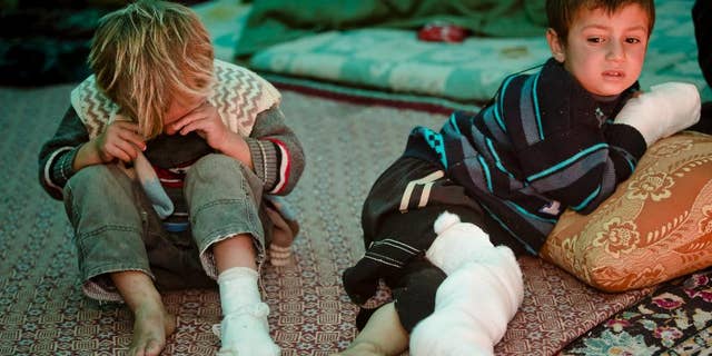 Mahmut Munir, 8 years-old, right, a Syrian Kurdish refugee boy from Kobani and his 5 year-old brother Mahmut, left, who were injured along with other family members in a mortar attack by forces of the Islamic State group sits in a tent at a camp in Suruc, on the Turkey-Syria border Wednesday, Nov. 19, 2014. Kobani, also known as Ayn Arab, and its surrounding areas, has been under assault by extremists of the Islamic State group since mid-September and is being defended by Kurdish fighters. (AP Photo/Vadim Ghirda)