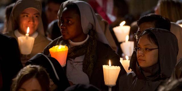 Faithful attend the Via Crucis (Way of the Cross) torchlight procession celebrated by Pope Francis in front of the Colosseum on Good Friday in Rome, Friday, April 18, 2014. (AP Photo/Gregorio Borgia)