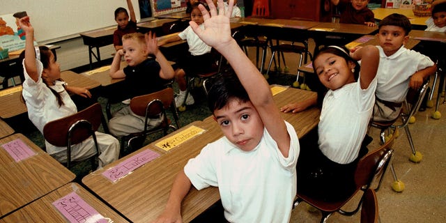 Hispanic students raise their hands to answer a question during a class taught in Spanish at Birdwell Elementary School September 11, 2003 in Tyler, Texas. (Photo by Mario Villafuerte/Getty Images)