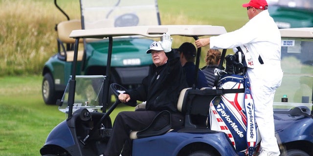 President Trump waves as he golfs on Saturday in western Scotland.