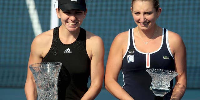 Simona Halep of Romania, left, and Timea Bacsinszky of Switzerland pose with their trophies after their final match of the WTA Shenzhen Open tennis tournament in Shenzhen in southern China's Guangdong province Saturday, Jan. 10, 2015. Halep beat Bacsinszky 2-0 in the final. (AP Photo) CHINA OUT