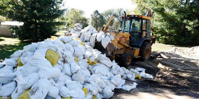 A Waterloo City worker removes sandbags piled up on Belle Street after the Cedar River receded from homes in the area Monday, Sept. 26, 2016, in Cedar Falls, Iowa. (Matthew Putney/The Waterloo Courier via AP)