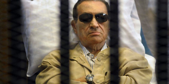 FILE - In this June 2, 2012 file photo, Egypt's ex-President Hosni Mubarak lays on a gurney inside a barred cage in the police academy courthouse in Cairo, Egypt. An Egyptian security official says ousted president Hosni Mubarak has been interrogated over gifts worth millions of Egyptian pounds (hundreds of thousands of US dollars) he allegedly received from the country's top newspaper as a show of loyalty while he was in power. Mubarak is serving a life sentence after being convicted for failing to stop killings of protesters during 2011 uprising. (AP Photo/File)