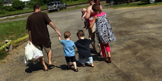 OSWEGO, NY - JUNE 20: Members of the Dolan family walk home with bags of food after a food distribution by the Food Bank of the Southern Tier Mobile Food Pantry on June 20, 2012 in Oswego, New York. The mobile food pantry program was introduced in 2007 in the Southern Tier of New York and covers nearly 4,000 predominately rural miles. The converted beverage truck delivers fresh produce, dairy products and other grocery items to individuals and families in need. The pantry typically distributes for a period of two hours and provides 100 to 160 families with food. According to the 2010 Census, 15.72% the population serviced by the mobile pantry live at or below the federal poverty level. According to statistics presented at a recent U.S. Senate committee hearing, almost one in seven Americans are living below the poverty line with a significant number of them being children. (Photo by Spencer Platt/Getty Images)