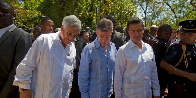 Chile's President Sebastian Pinera, left, Colombia's President Juan Manuel Santos, center, and Mexico's President Enrique Pena Nieto stroll through a hotel garden while taking a break from the Association of Caribbean States regional summit, in Port-au-Prince, Haiti. Friday April 26, 2013. Haiti wrapped up the international summit on Friday that brought together six presidents from the region who all signed an agreement that called for an end to the U.S. embargo against Cuba and to help the region better prepare for disasters. (AP Photo/Dieu Nalio Chery)