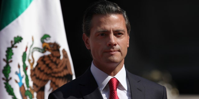 FILE - In this Nov. 3, 2014, file photo, Mexico's President Enrique Pena Nieto stands at attention as the national anthem of the UK and Mexico is played during an official visit by Britain's Prince Charles and his wife Camilla Duchess of Cornwall, at the National Palace in Mexico City. According to a report by a leading Mexican journalist, the private home of President Pena Nieto was built and is registered under the name of a company connected to a controversial high-speed rail contract that he abruptly canceled last week. The article did not specify what laws if any are broken by the president using a house registered under another name. (AP Photo/Marco Ugarte, File)