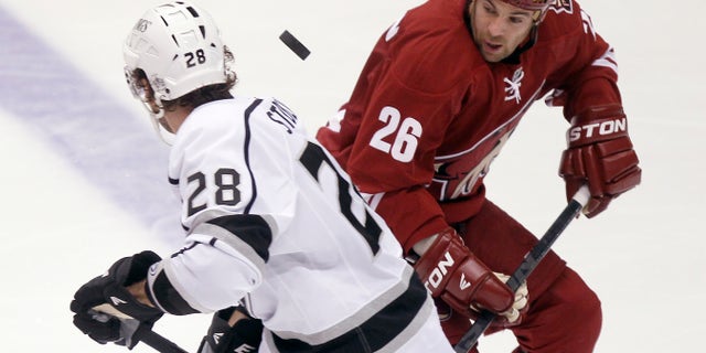 Los Angeles Kings center Jarret Stoll, left, and Phoenix Coyotes left winger Steve Sullivan, right, looks to gain control of a loose puck in the third period of an NHL hockey game Tuesday, April 2, 2013, in Glendale, Ariz. The Coyotes won 3-1. (AP Photo/Paul Connors)